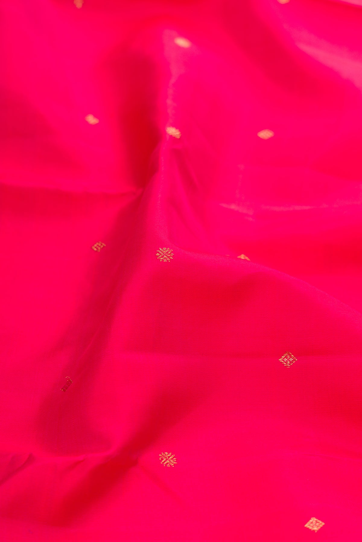 Close up of Pure Silk Pure Zari Pink Kanjivaram Saree with Zari Butta on the body and Zari Border.  displaying folds