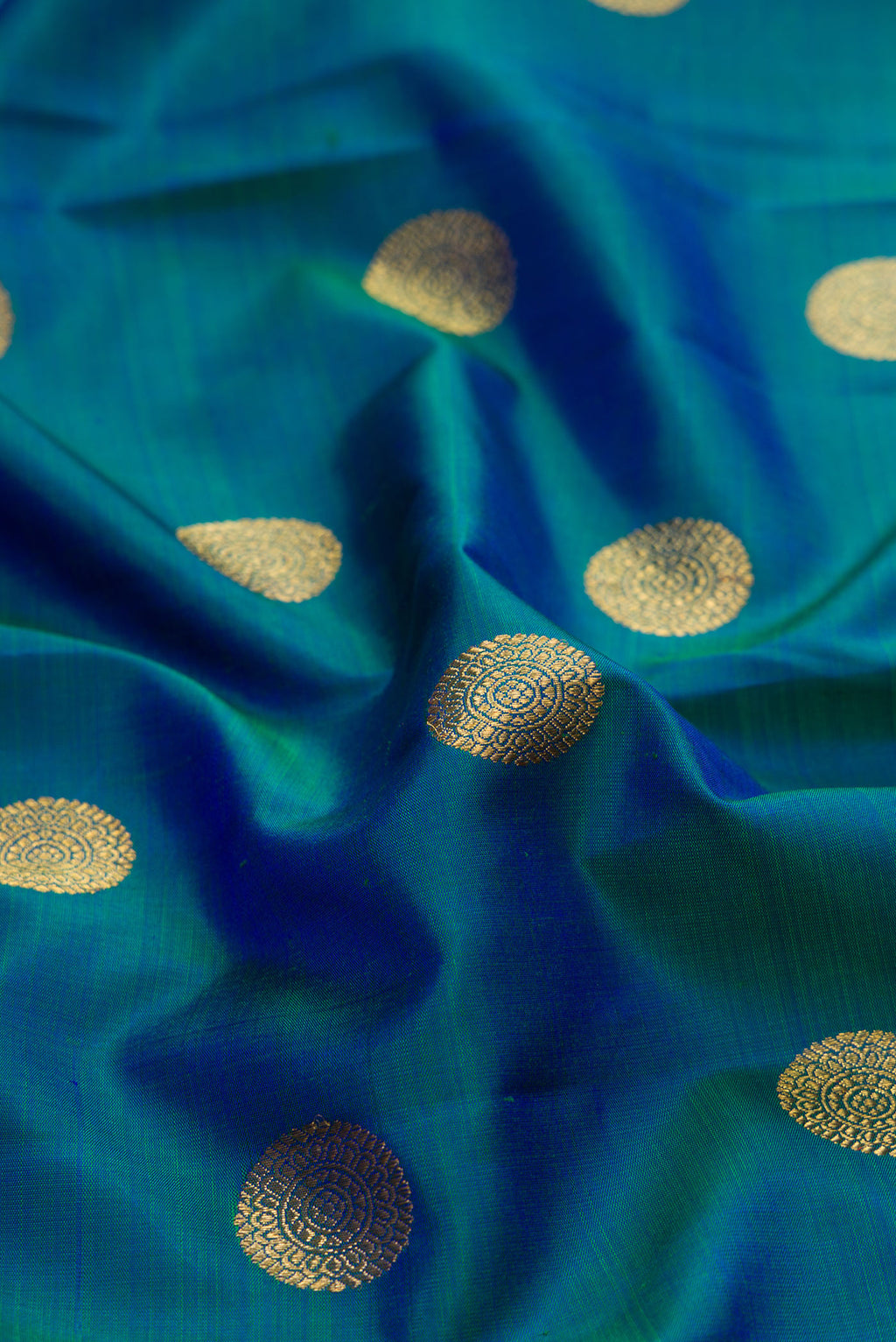 Close up of Pure Silk Pure Zari Peacock Blue Kanjivaram Saree with Zari Butta on the body and Zari Border.  displaying folds