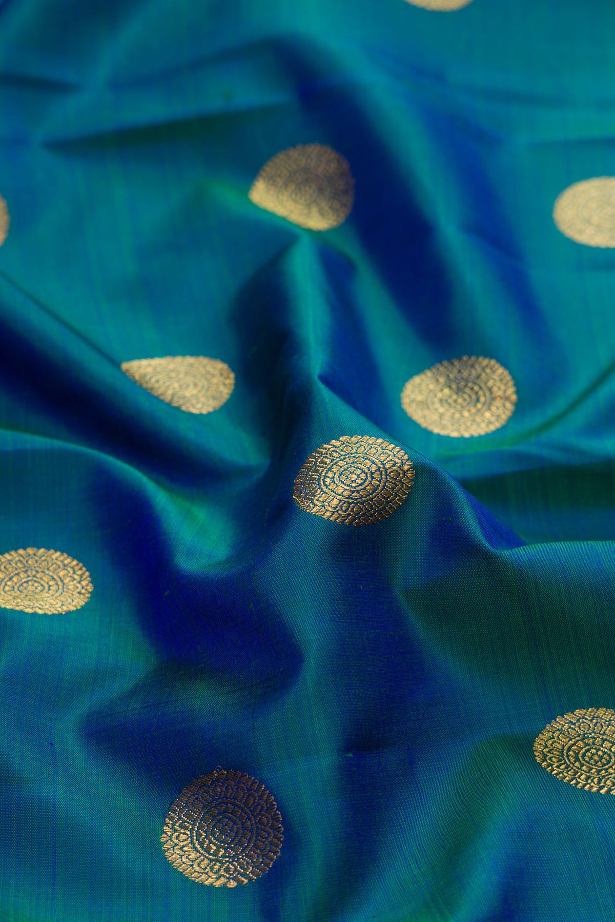 Close up of Pure Silk Pure Zari Peacock Blue Kanjivaram Saree with Zari Butta on the body and Zari Border.  displaying folds