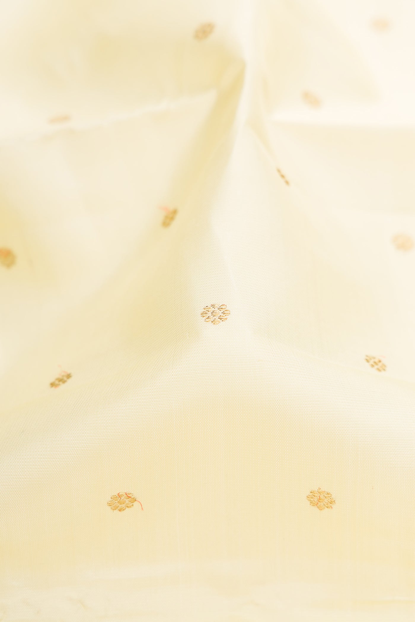 Close up of Pure Silk Pure Zari Cream Kanjivaram Saree with Zari Butta on the body and Zari Border.  displaying folds