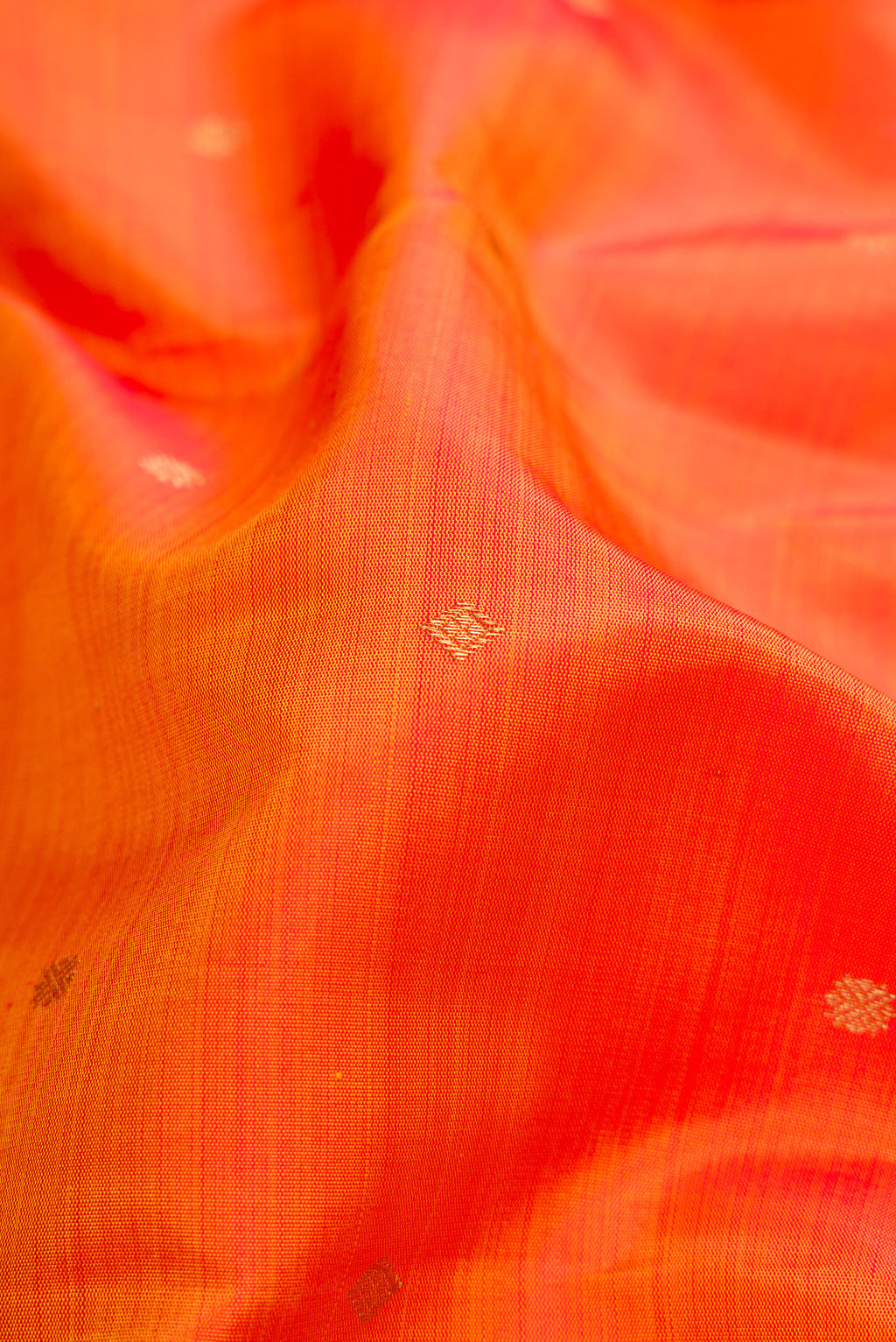 Close up of Orange Dual Tone Kanchipuram Silk Saree with Zari Butta on the body and Zari Border.  displaying folds
