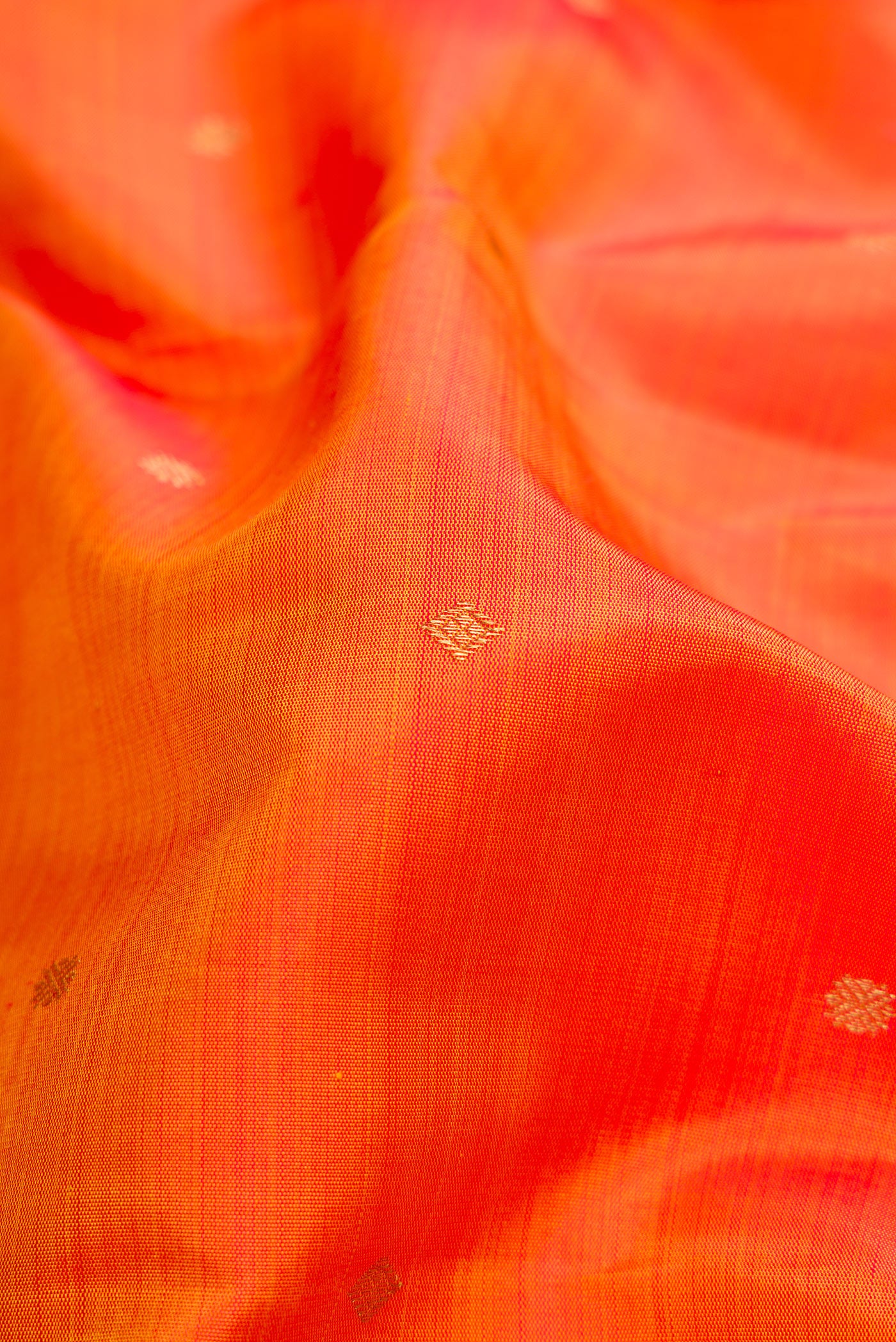 Close up of Orange Dual Tone Kanchipuram Silk Saree with Zari Butta on the body and Zari Border.  displaying folds