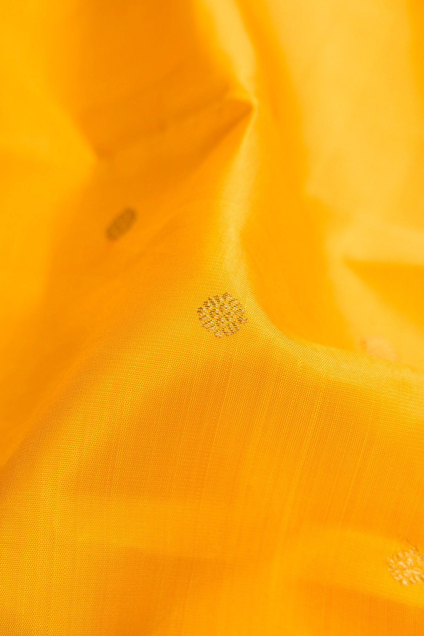 Close up of Pure Silk Pure Zari Yellow Dual Tone Kanjivaram Saree with Zari Butta on the body and Zari Border.  displaying folds