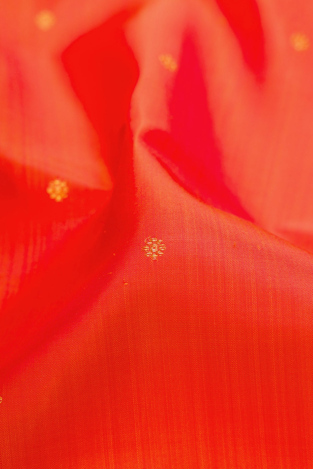 Close up of Orange Dual Tone Kanchipuram Silk Saree with Zari Butta on the body and Zari Border.  displaying folds