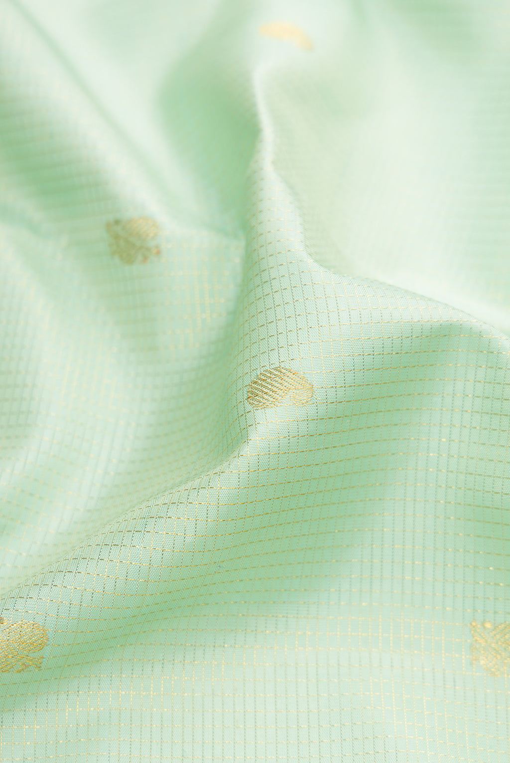 Close up of Mint Green Kanchipuram Silk Saree with Checked design on the body and Zari Border.  displaying folds