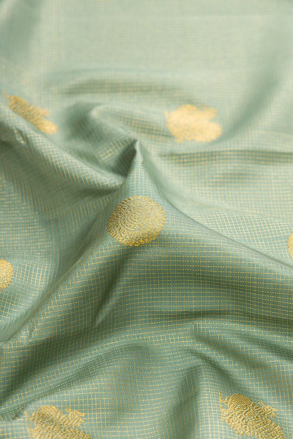 Close up of Green Dual Tone Kanchipuram Silk Saree with Checked design on the body and Fancy Border.  displaying folds
