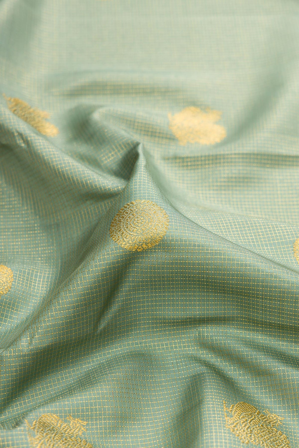 Close up of Green Dual Tone Kanchipuram Silk Saree with Checked design on the body and Fancy Border.  displaying folds
