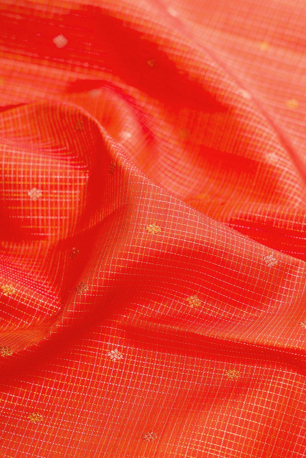 Close up of Orange Kanjivaram Silk Saree with Checked design on the body and Fancy Border.  displaying folds