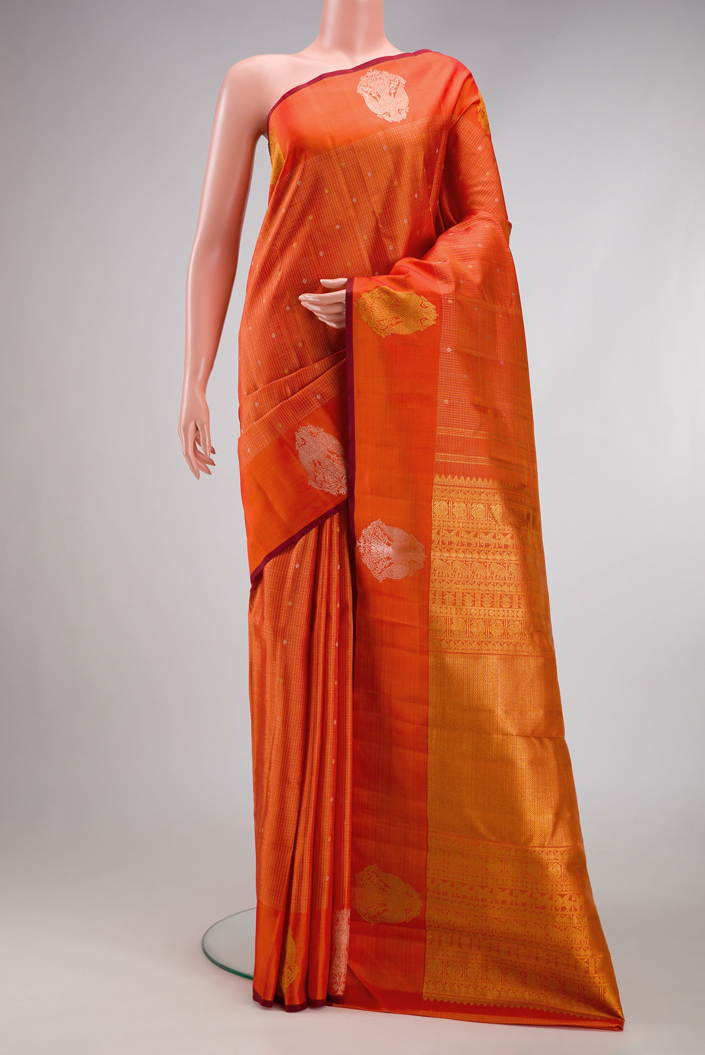 Orange Kanjivaram Silk Saree with Checked design on the body and Fancy Border.  displayed on a mannequin