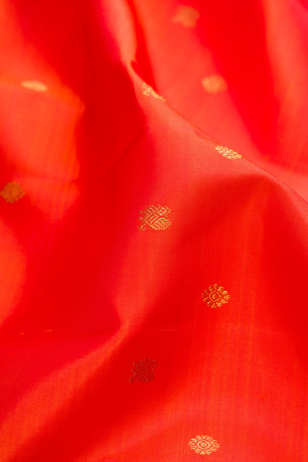 Close up of Orange Kanchipuram Silk Saree with Zari Butta on the body and Zari Border.  displaying folds