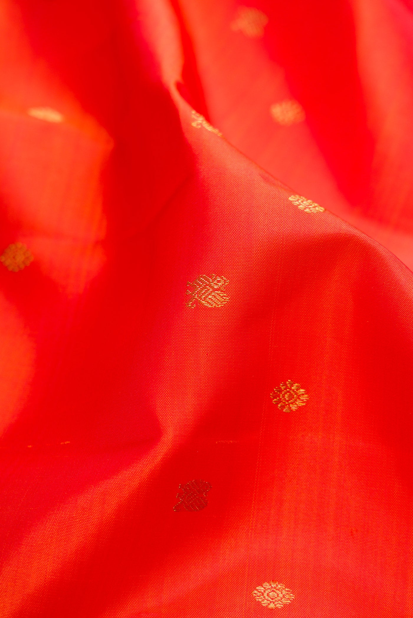 Close up of Orange Kanchipuram Silk Saree with Zari Butta on the body and Zari Border.  displaying folds