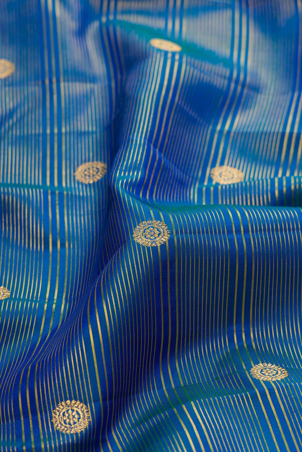 Close up of Peacock Blue Kanchipuram Silk Saree with Zari Butta on the body and Zari Border.  displaying folds