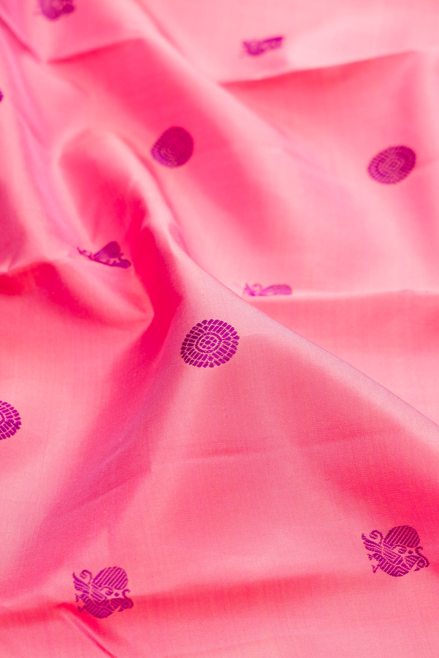 Close up of Pure Silk Pure Zari Pink Kanchipuram Saree with Thread Butta on the body and Zari Border.  displaying folds