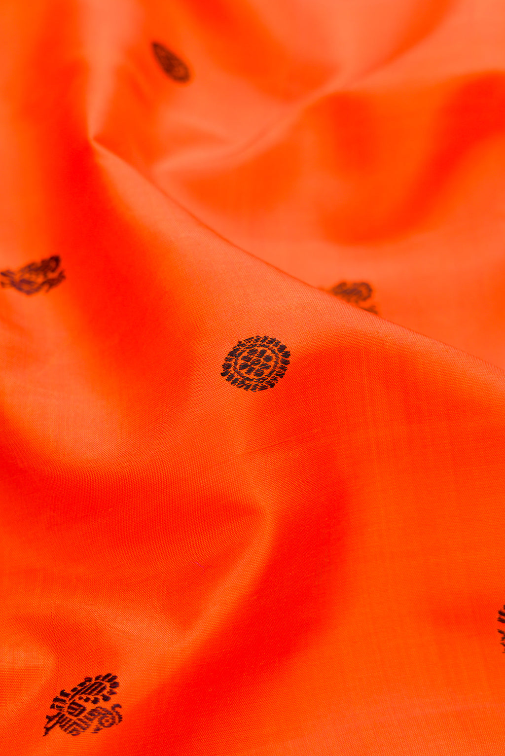 Close up of Orange Kanjivaram Silk Saree with Thread Butta on the body and Zari Border.  displaying folds