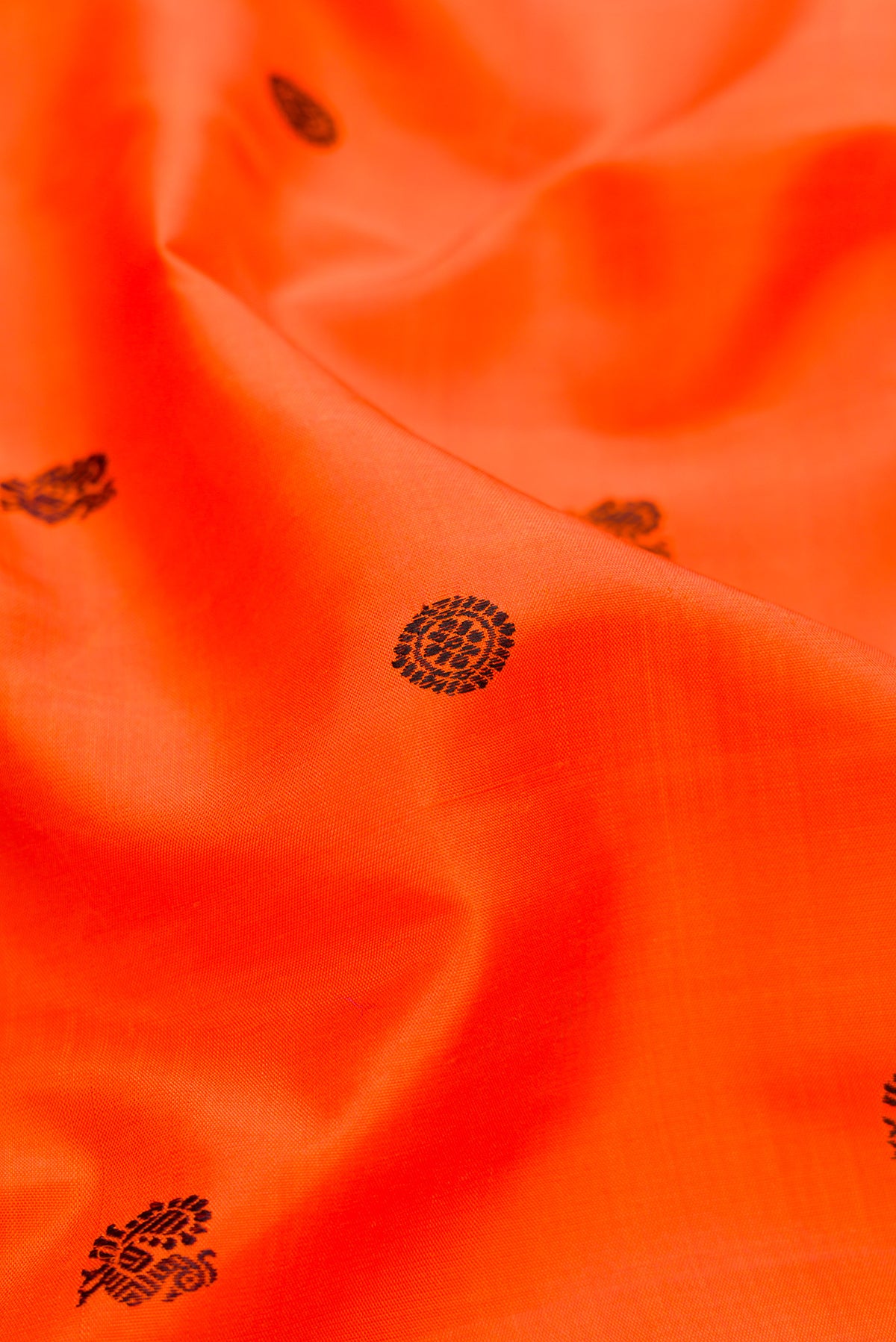 Close up of Orange Kanjivaram Silk Saree with Thread Butta on the body and Zari Border.  displaying folds