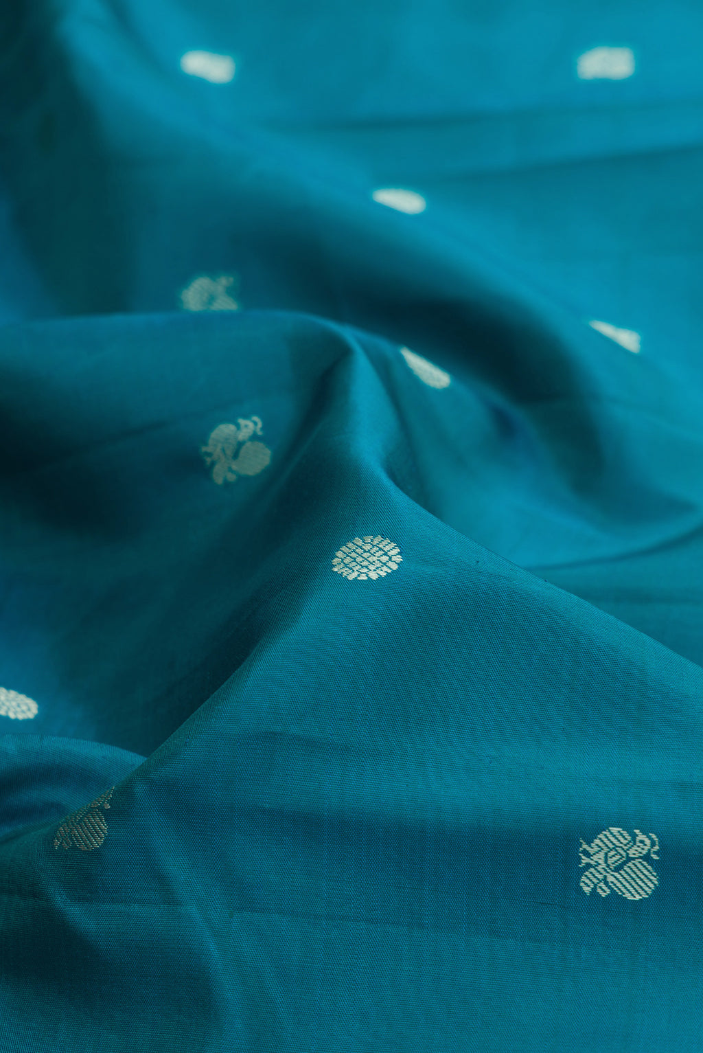 Close up of Blue Kanjivaram Silk Saree with Thread Butta on the body and Thread Border.  displaying folds