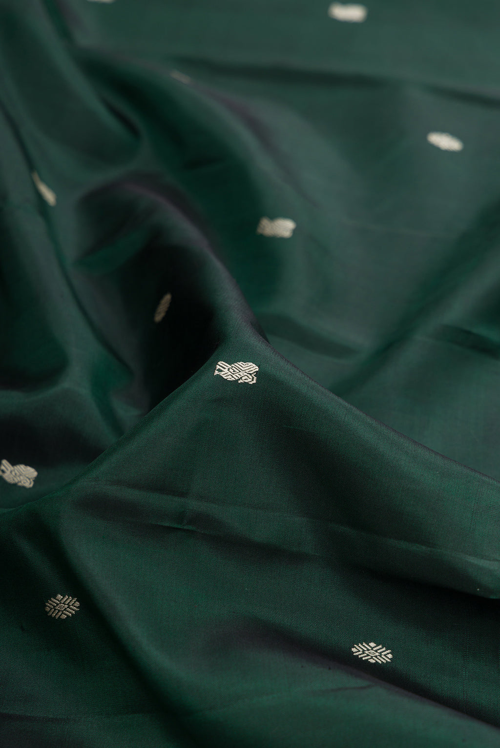 Close up of Bottle Green Kanchipuram Silk Saree with Thread Butta on the body and Thread Border.  displaying folds