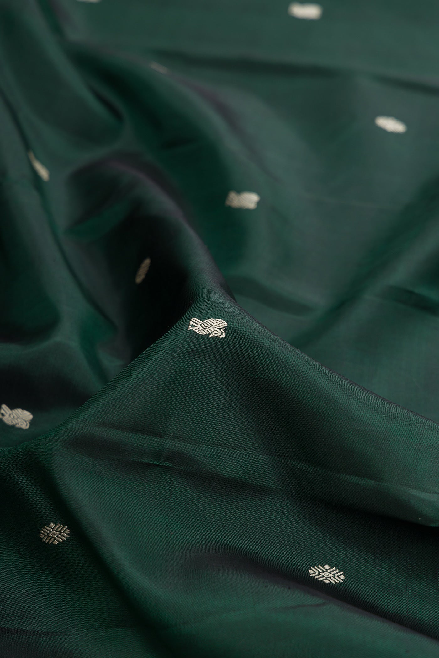 Close up of Bottle Green Kanchipuram Silk Saree with Thread Butta on the body and Thread Border.  displaying folds