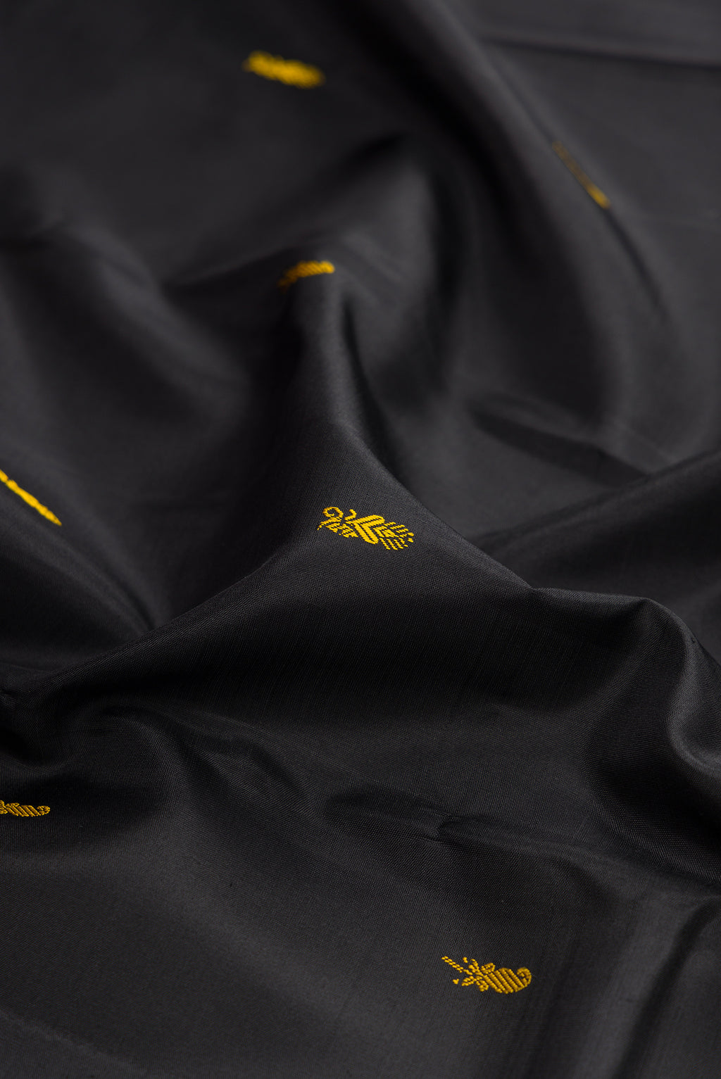 Close up of Black Kanchipuram Silk Saree with Thread Butta on the body and Thread Border.  displaying folds