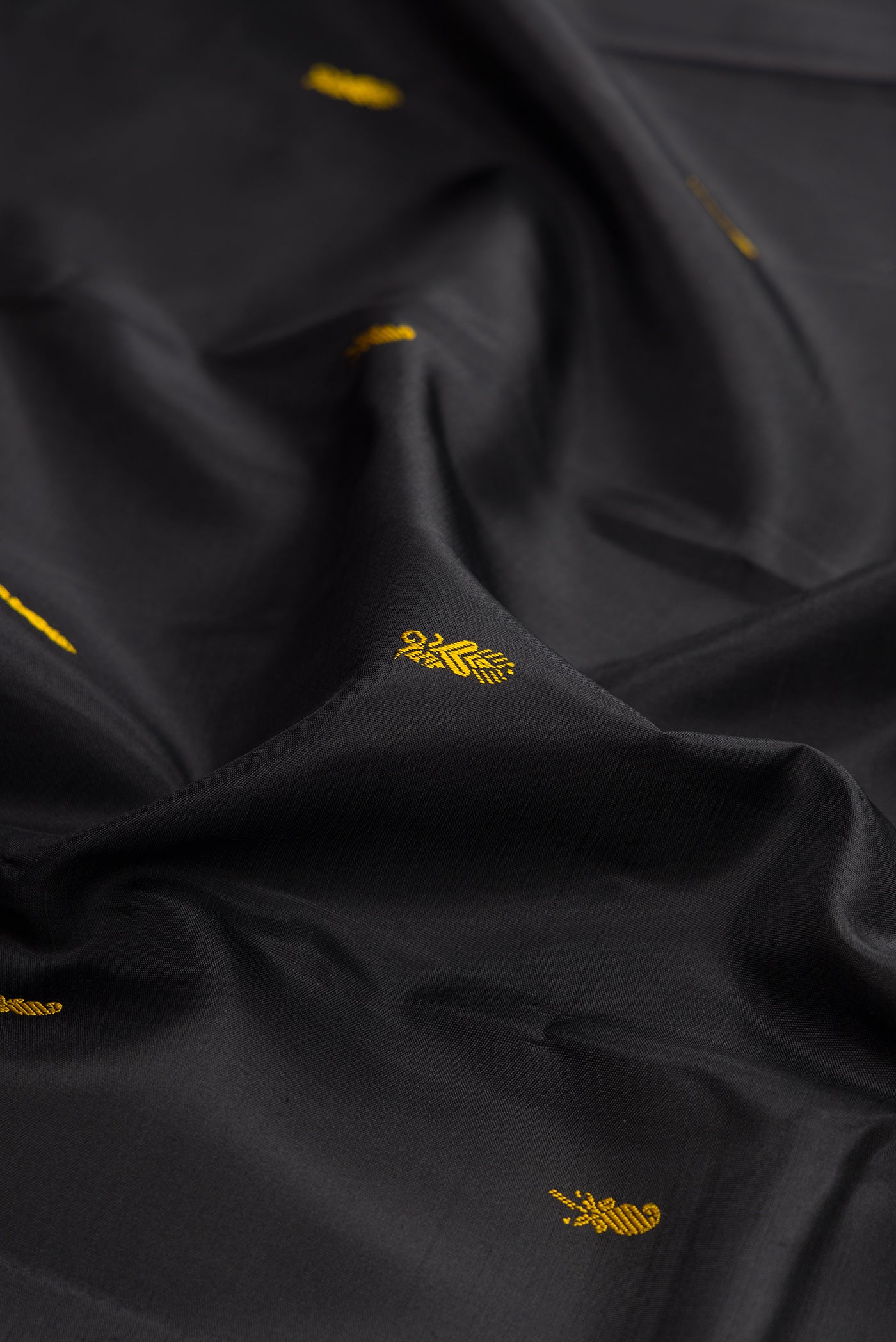 Close up of Black Kanchipuram Silk Saree with Thread Butta on the body and Thread Border.  displaying folds