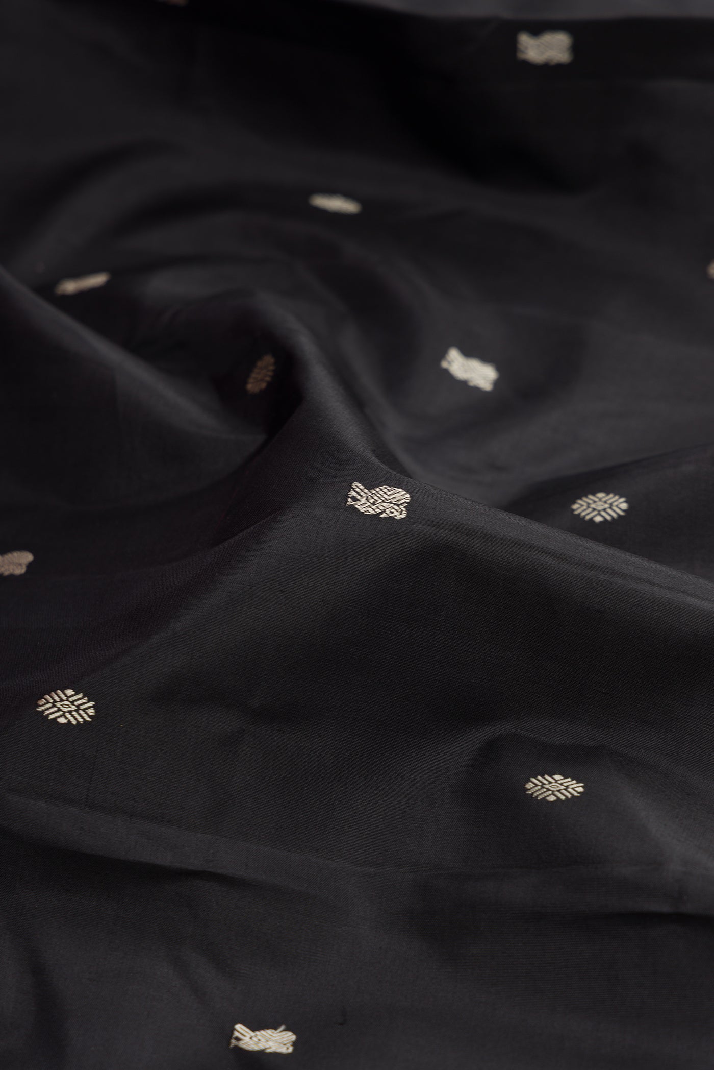 Close up of Black Kanchipuram Silk Saree with Thread Butta on the body and Thread Border.  displaying folds