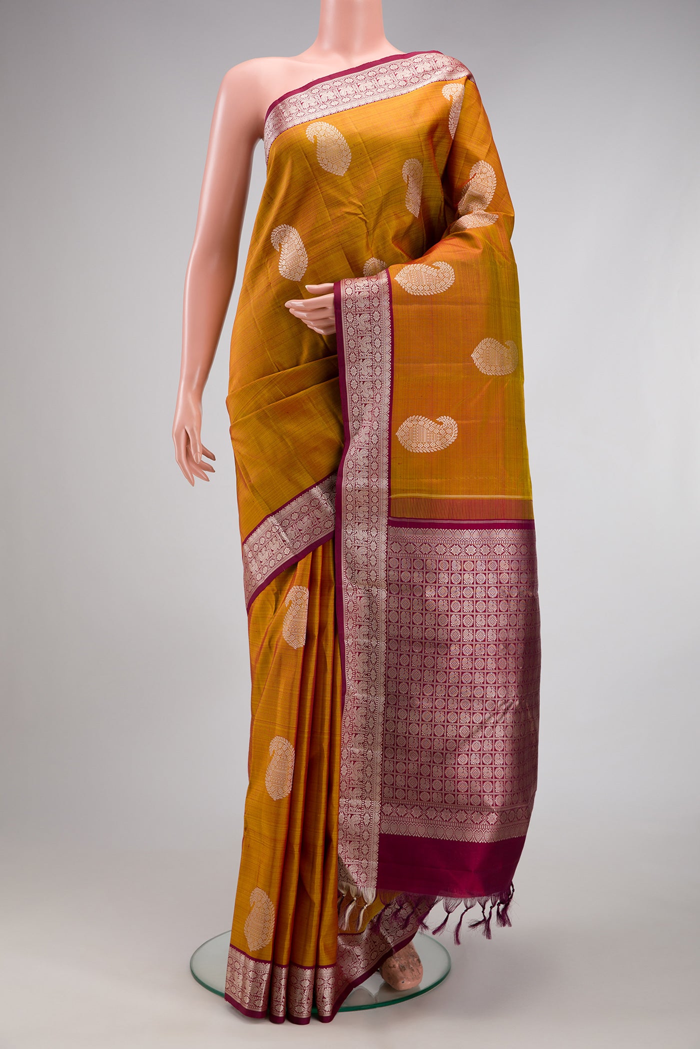 Mustard Kanjivaram Silk Saree with Thread Butta on the body and Thread Border.  displayed on a mannequin