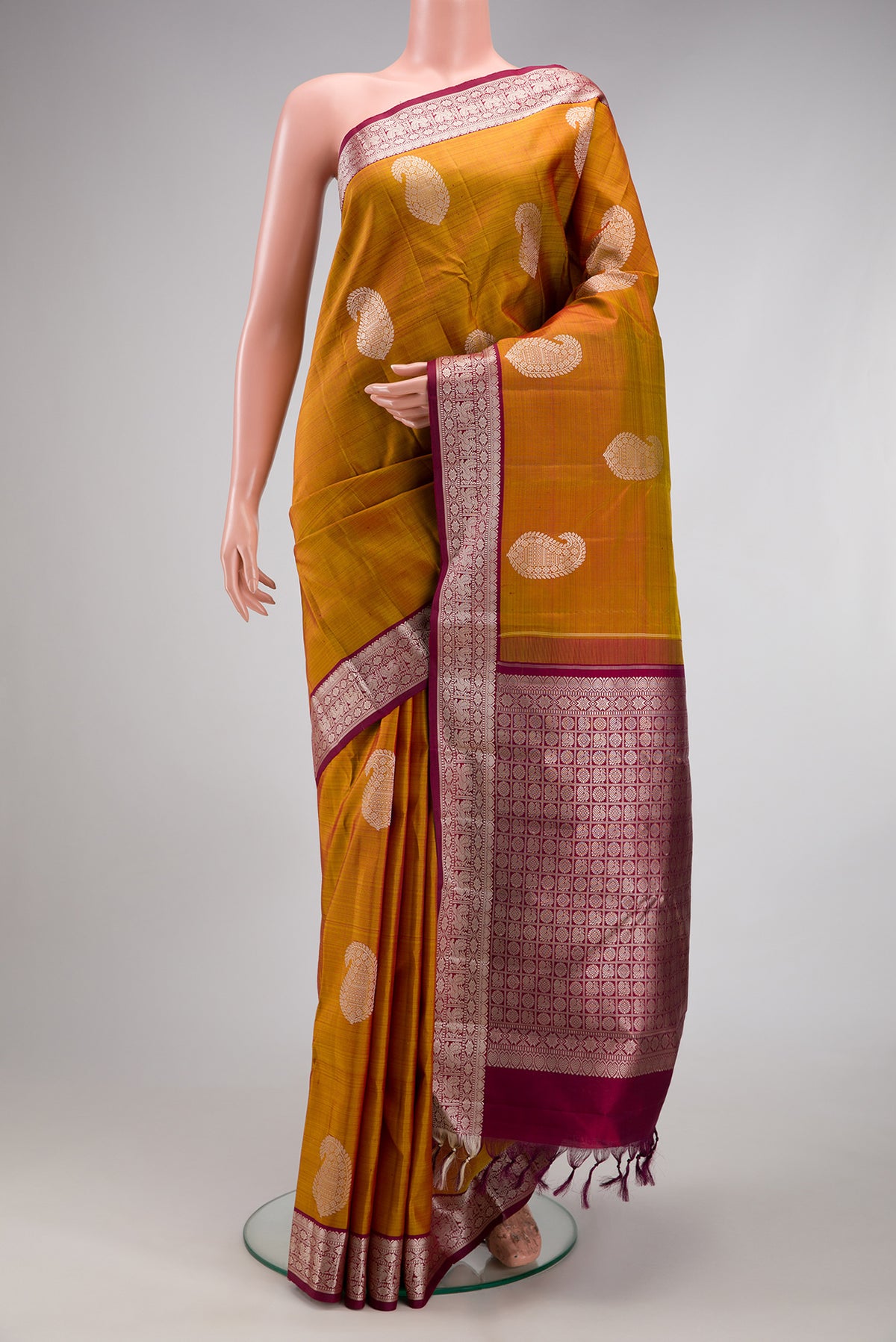 Mustard Kanjivaram Silk Saree with Thread Butta on the body and Thread Border.  displayed on a mannequin