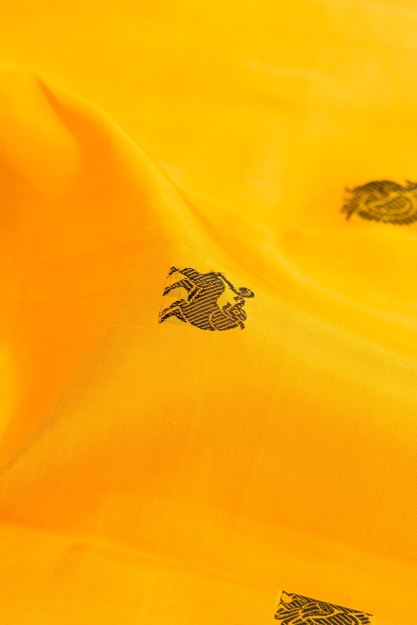 Close up of Yellow Kanjivaram Silk Saree with Thread Butta on the body and Thread Border.  displaying folds