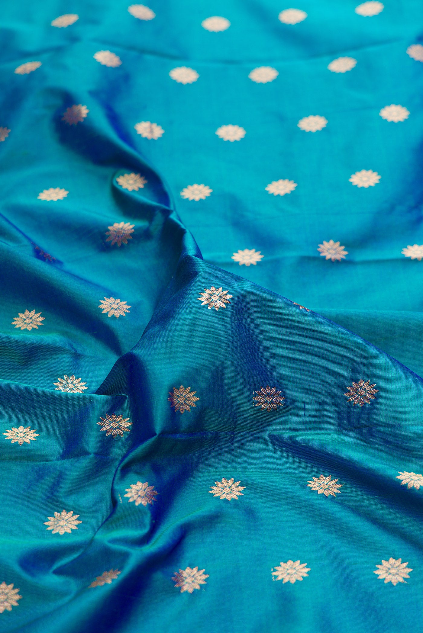 Close up of Peacock Blue Paithani Silk Saree with Zari Butta on the body and Zari Border.  displaying folds