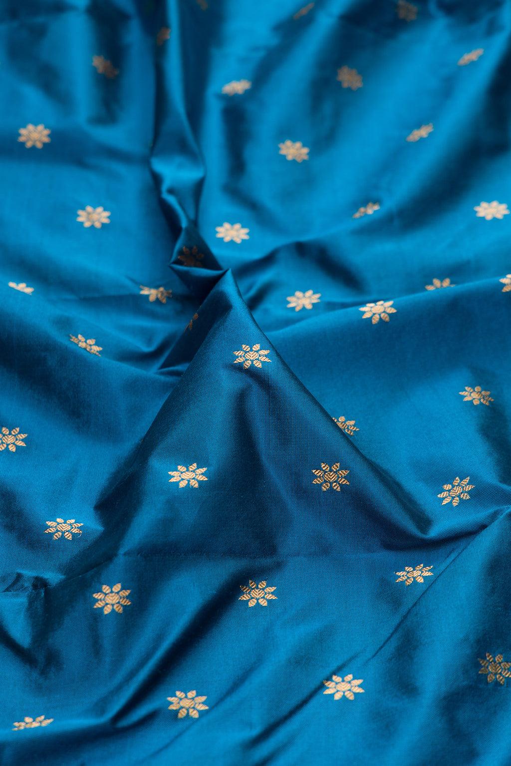 Close up of Peacock Blue Paithani Silk Saree with Zari Butta on the body and Zari Border.  displaying folds