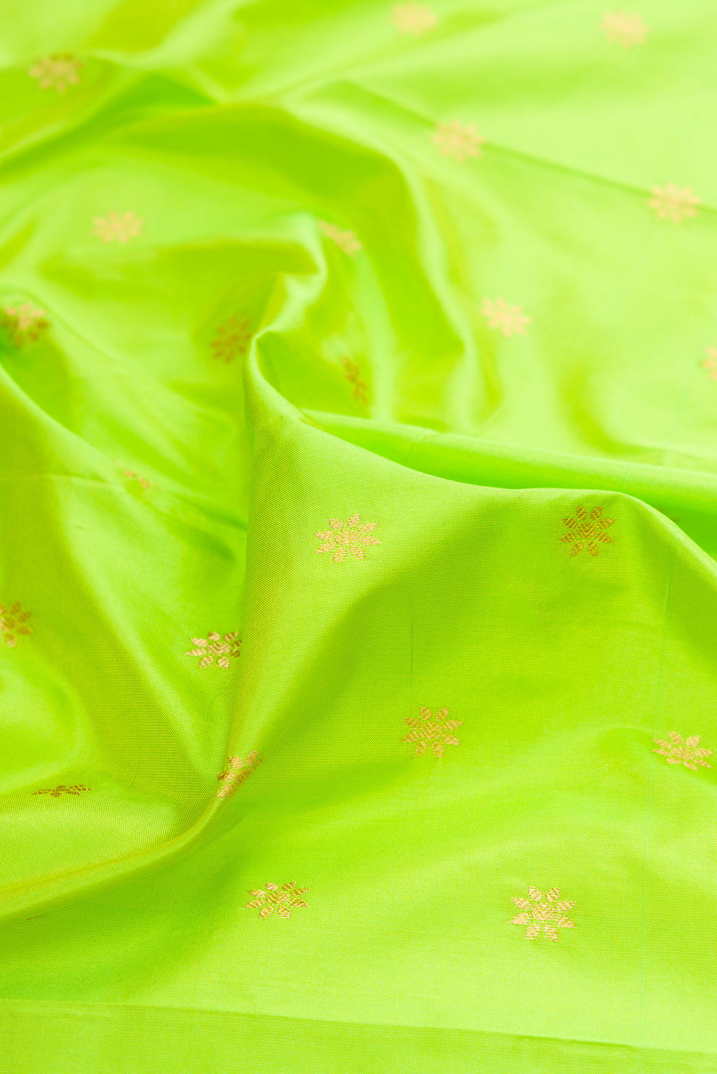 Close up of Parrot Green Paithani Silk Saree with Zari Butta on the body and Zari Border.  displaying folds