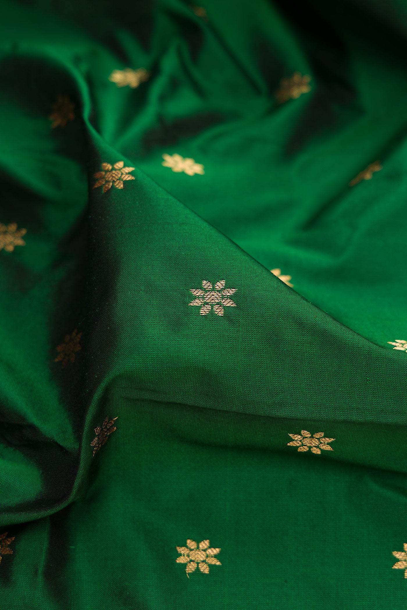 Close up of Bottle Green Paithani Silk Saree with Zari Butta on the body and Zari Border.  displaying folds