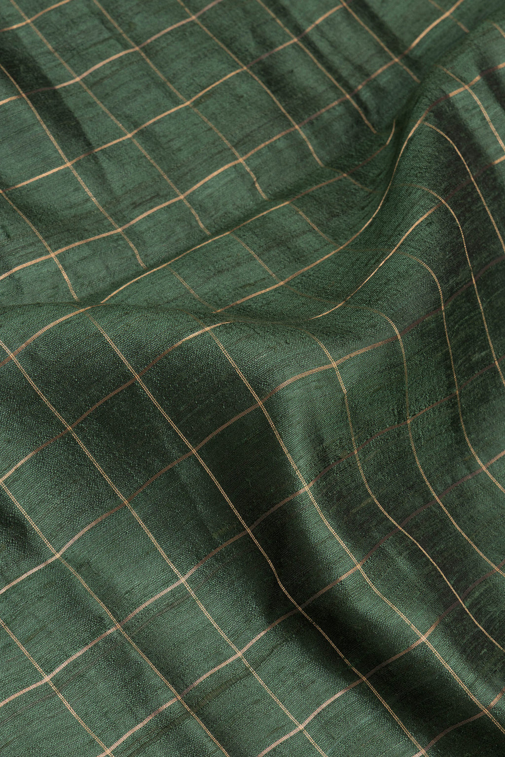 Close up of Green Tussar Silk Saree with Checked design on the body and Zari Border.  displaying folds