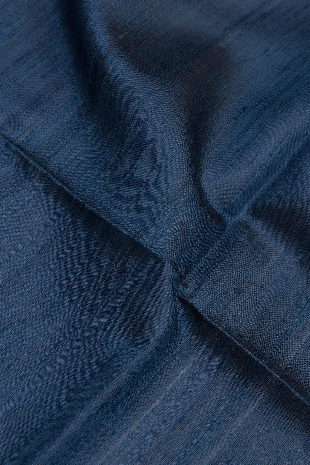 Close up of Navy Blue Tussar Silk Saree with Plain Body and Zari Border.  displaying folds