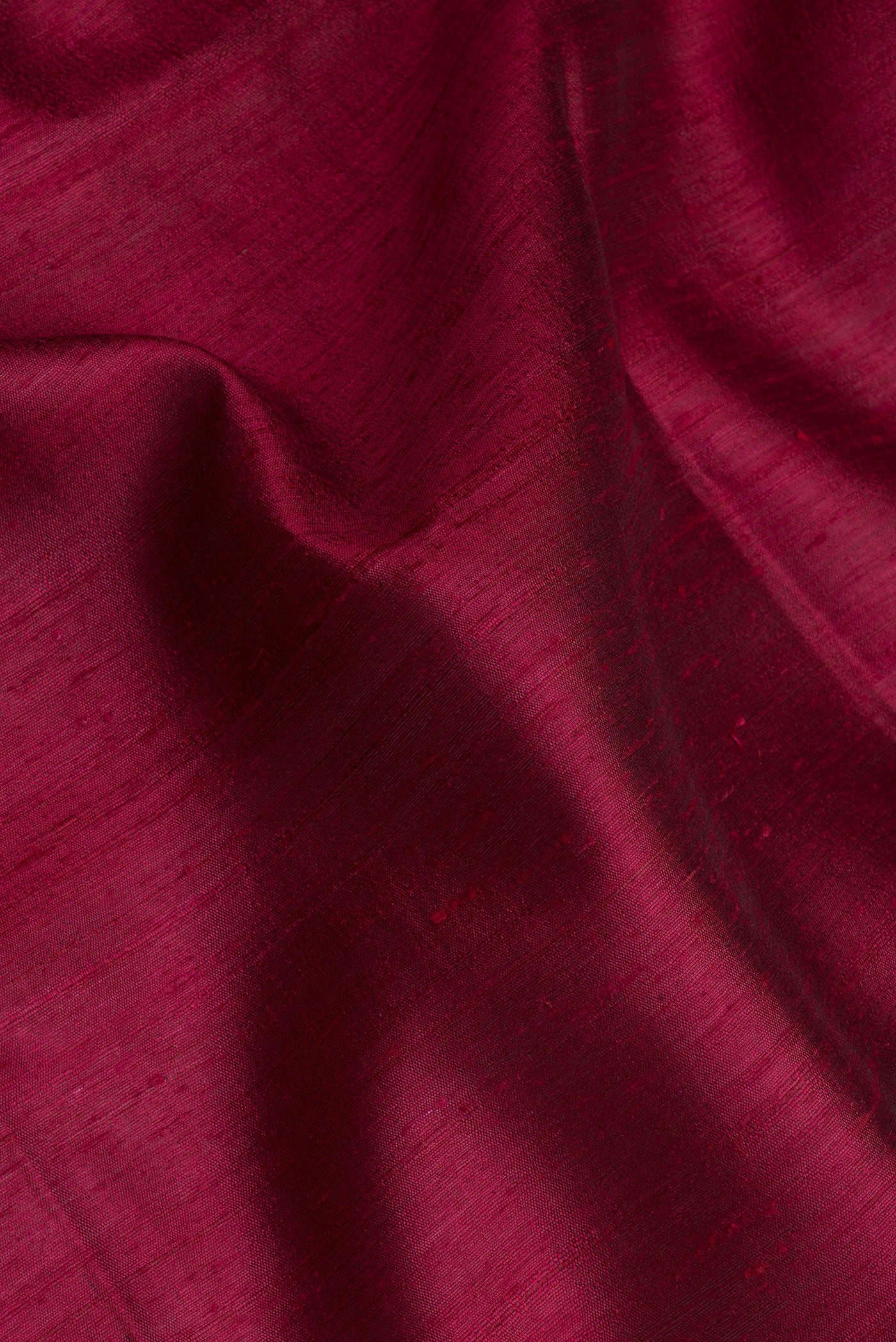 Close up of Maroon Tussar Silk Saree with Plain Body and Zari Border.  displaying folds