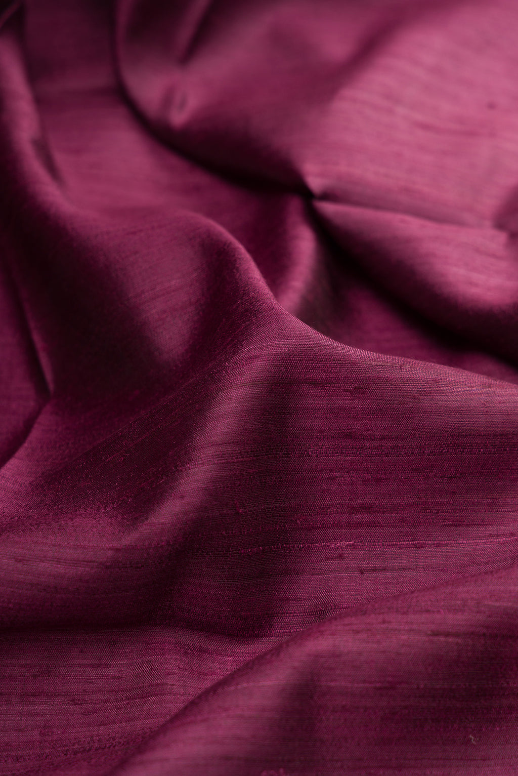 Close up of Magenta Tussar Silk Saree with Plain Body and Zari Border.  displaying folds