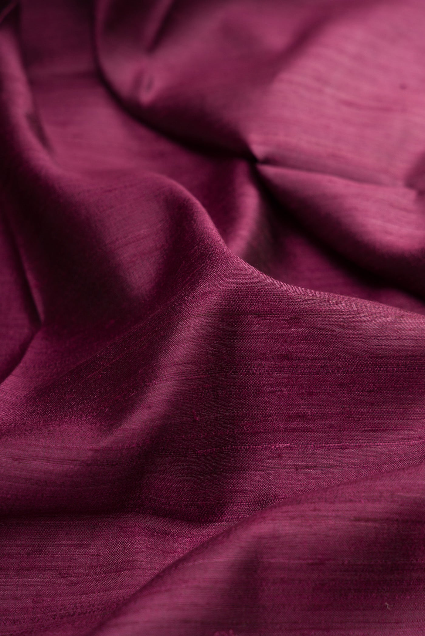 Close up of Magenta Tussar Silk Saree with Plain Body and Zari Border.  displaying folds