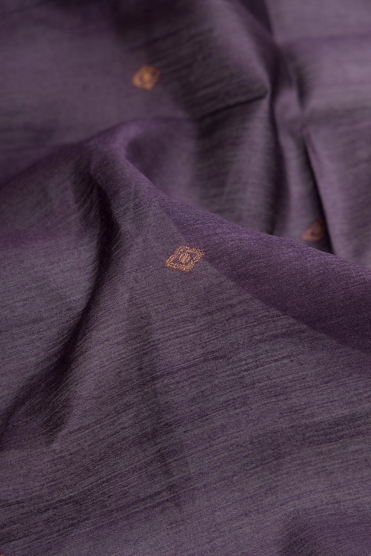 Close up of Purple Tussar Silk Saree with Zari Butta on the body and Printed Border.  displaying folds