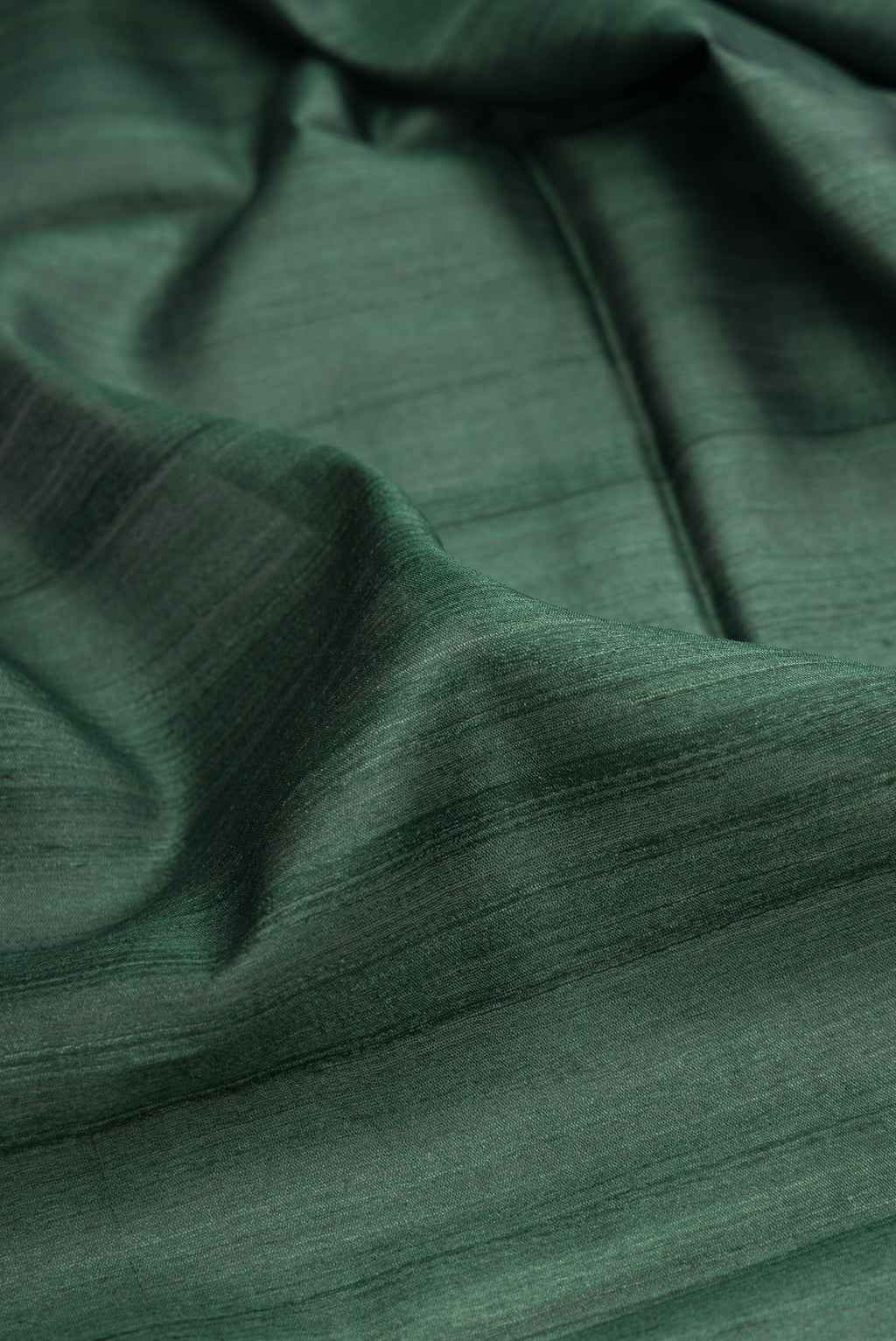 Close up of Bottle Green Tussar Silk Saree with Plain Body and Zari Border.  displaying folds