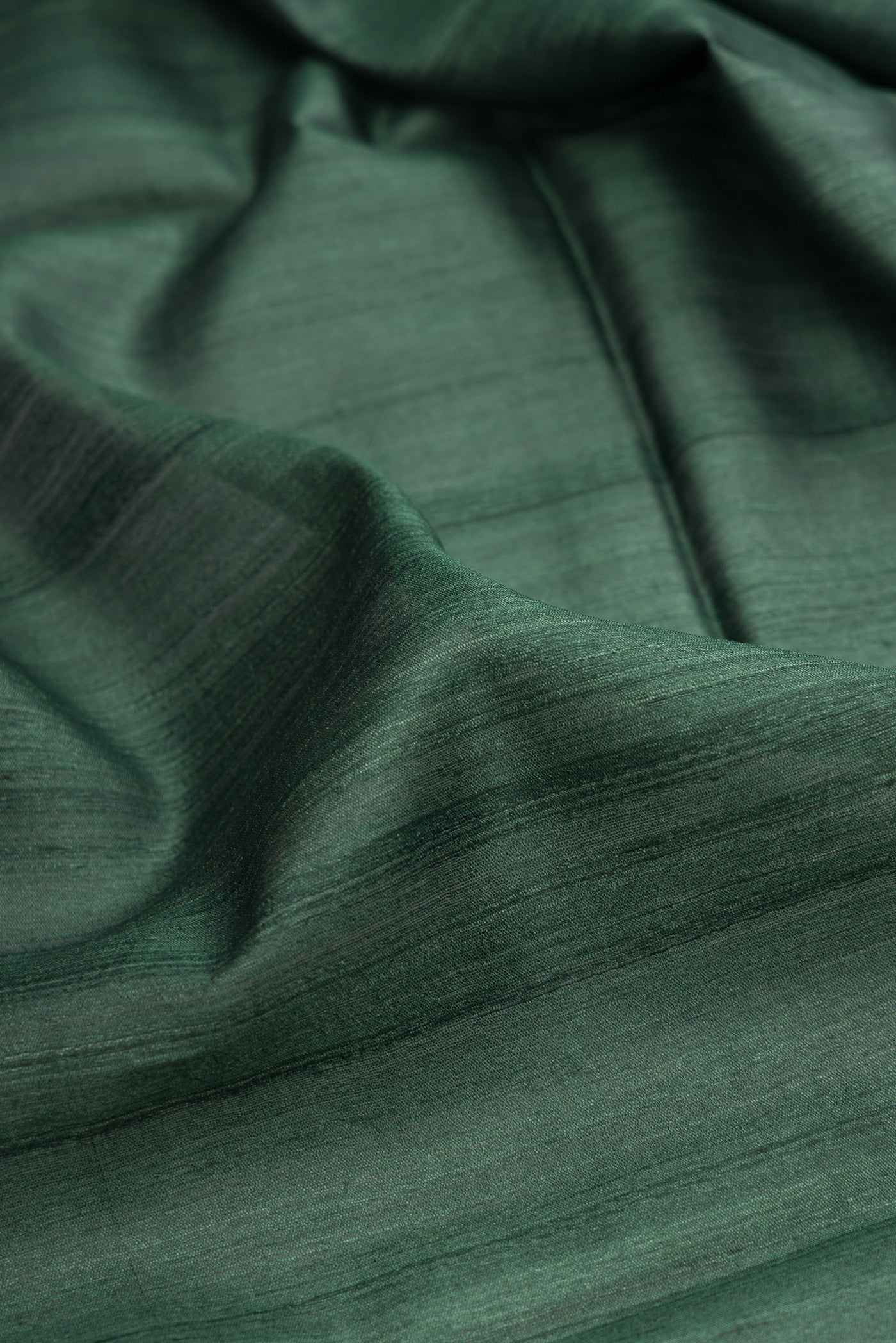 Close up of Bottle Green Tussar Silk Saree with Plain Body and Zari Border.  displaying folds