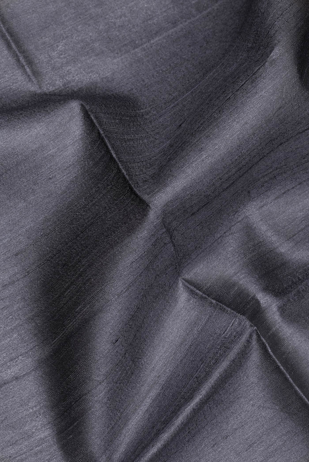 Close up of Grey Tussar Silk Saree with Plain Body and Zari Border.  displaying folds