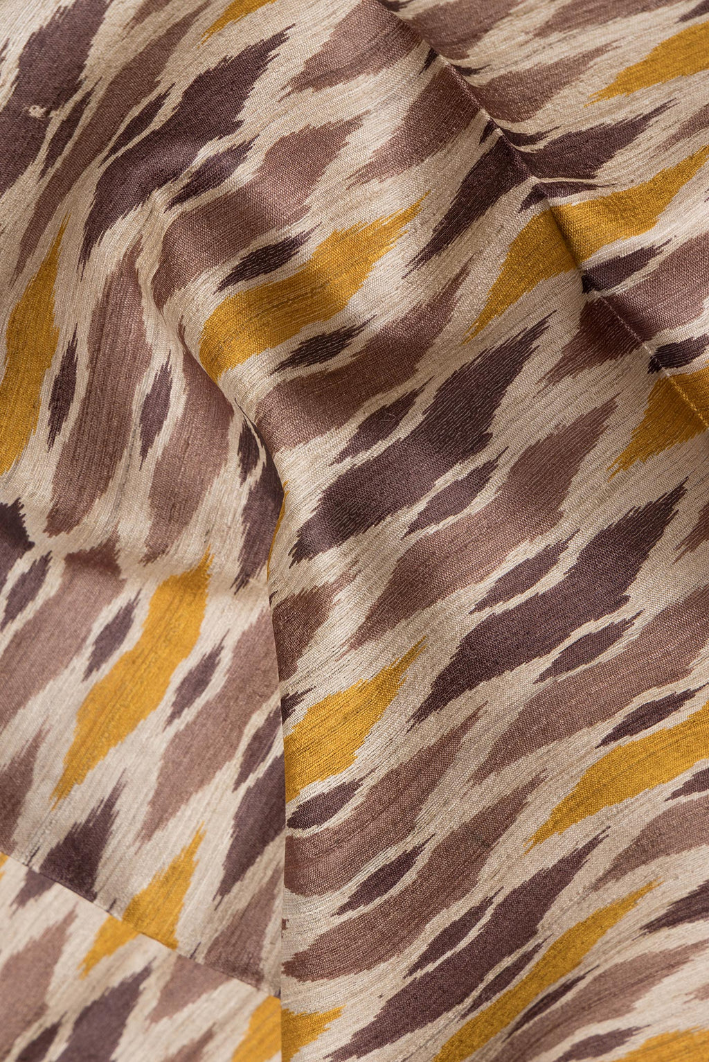 Close up of Beige Tussar Silk Saree with Ikat Print on the body and Thread Border.  displaying folds