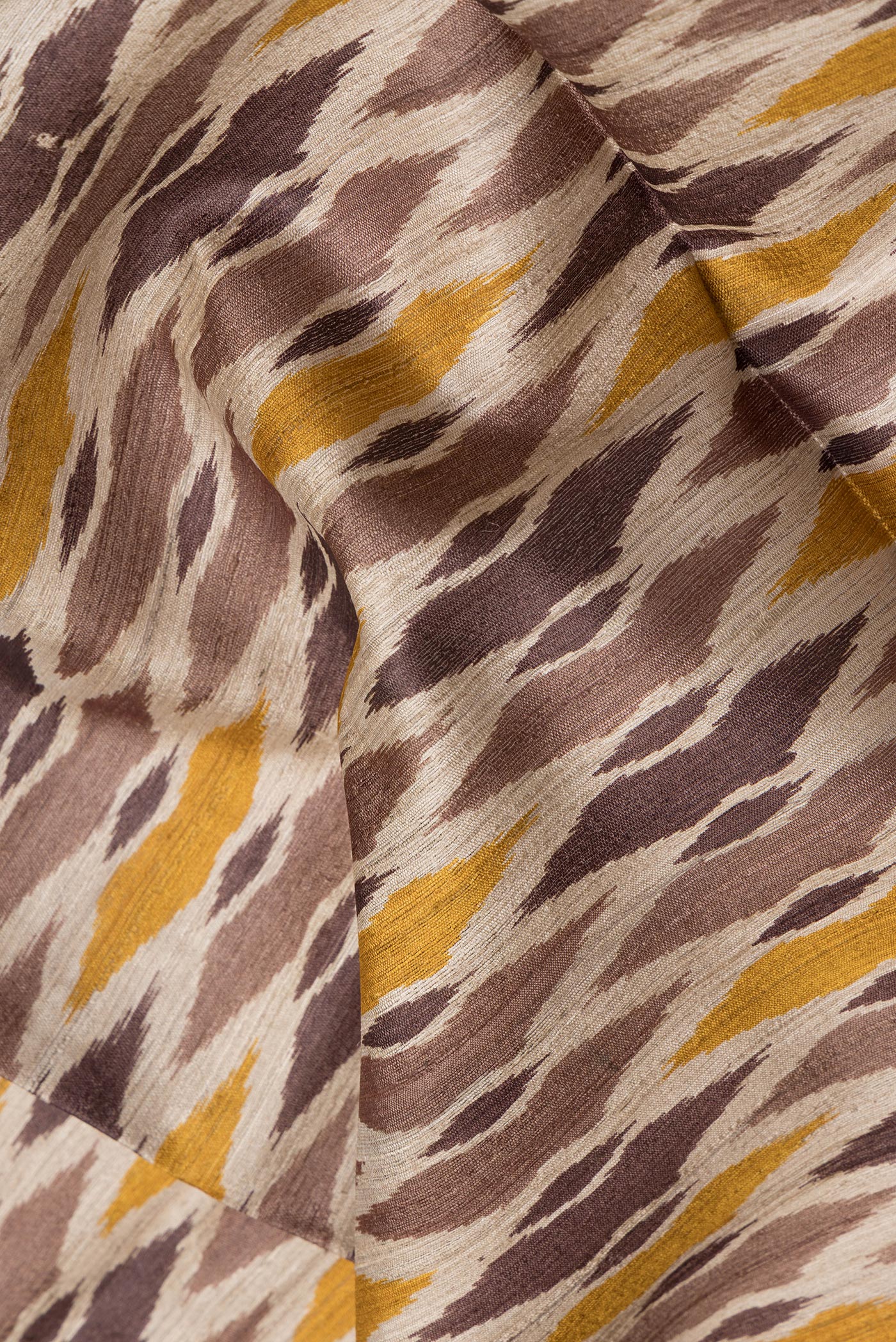 Close up of Beige Tussar Silk Saree with Ikat Print on the body and Thread Border.  displaying folds