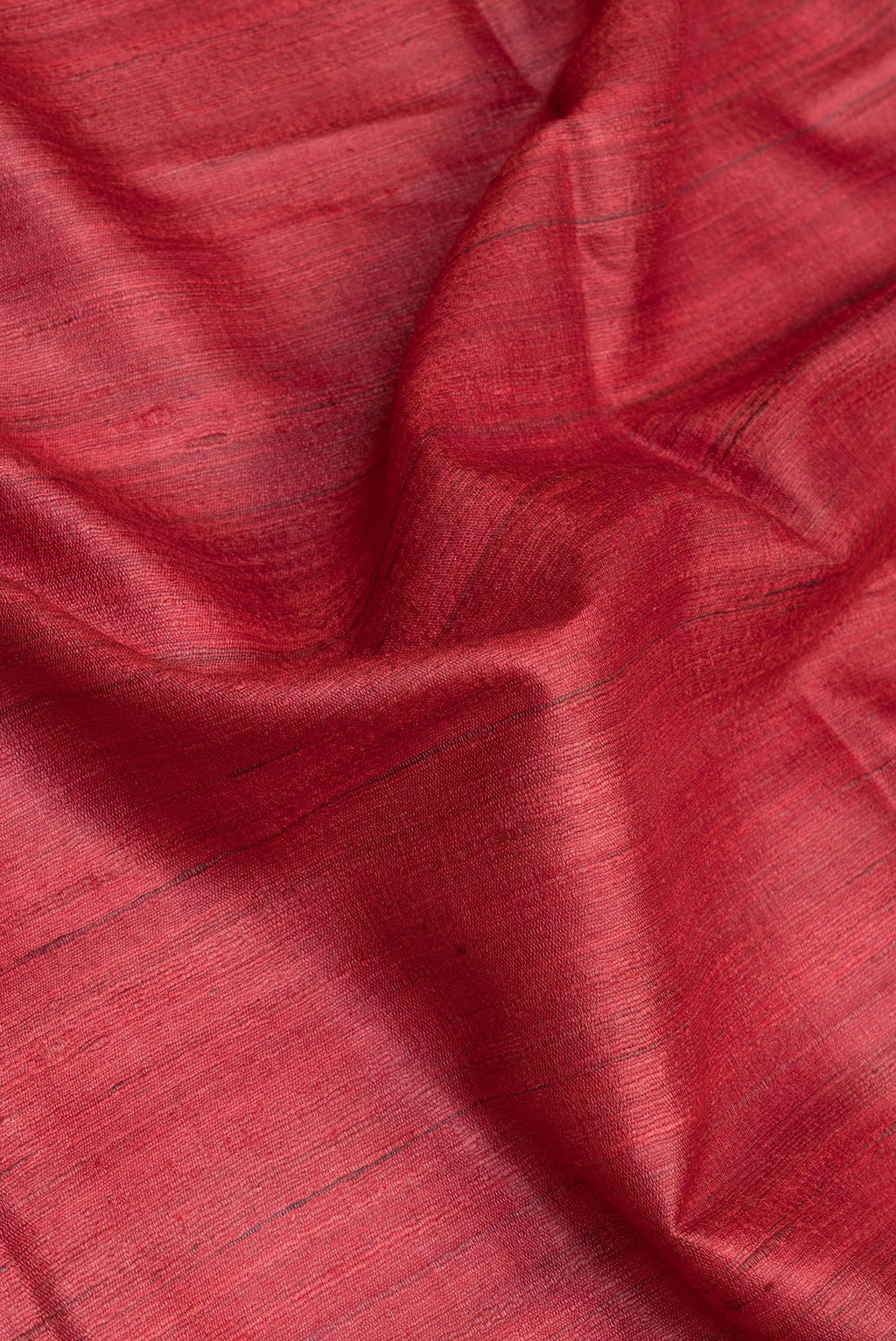 Close up of Red Tussar Silk Saree with Plain Body and Fancy Border.  displaying folds