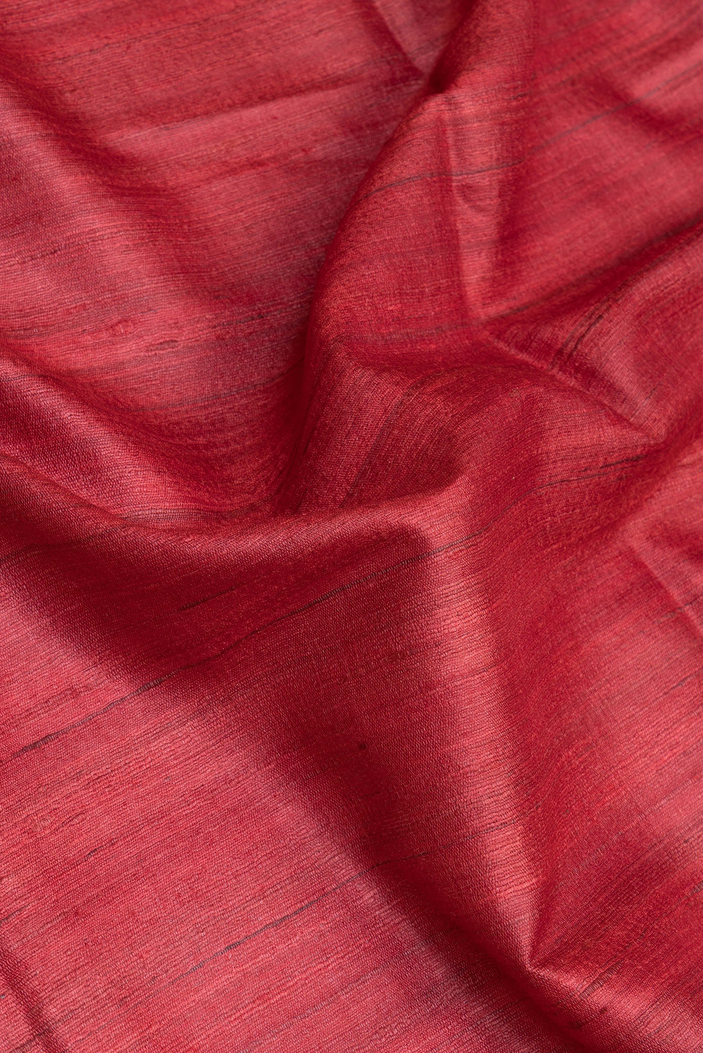 Close up of Red Tussar Silk Saree with Plain Body and Fancy Border.  displaying folds