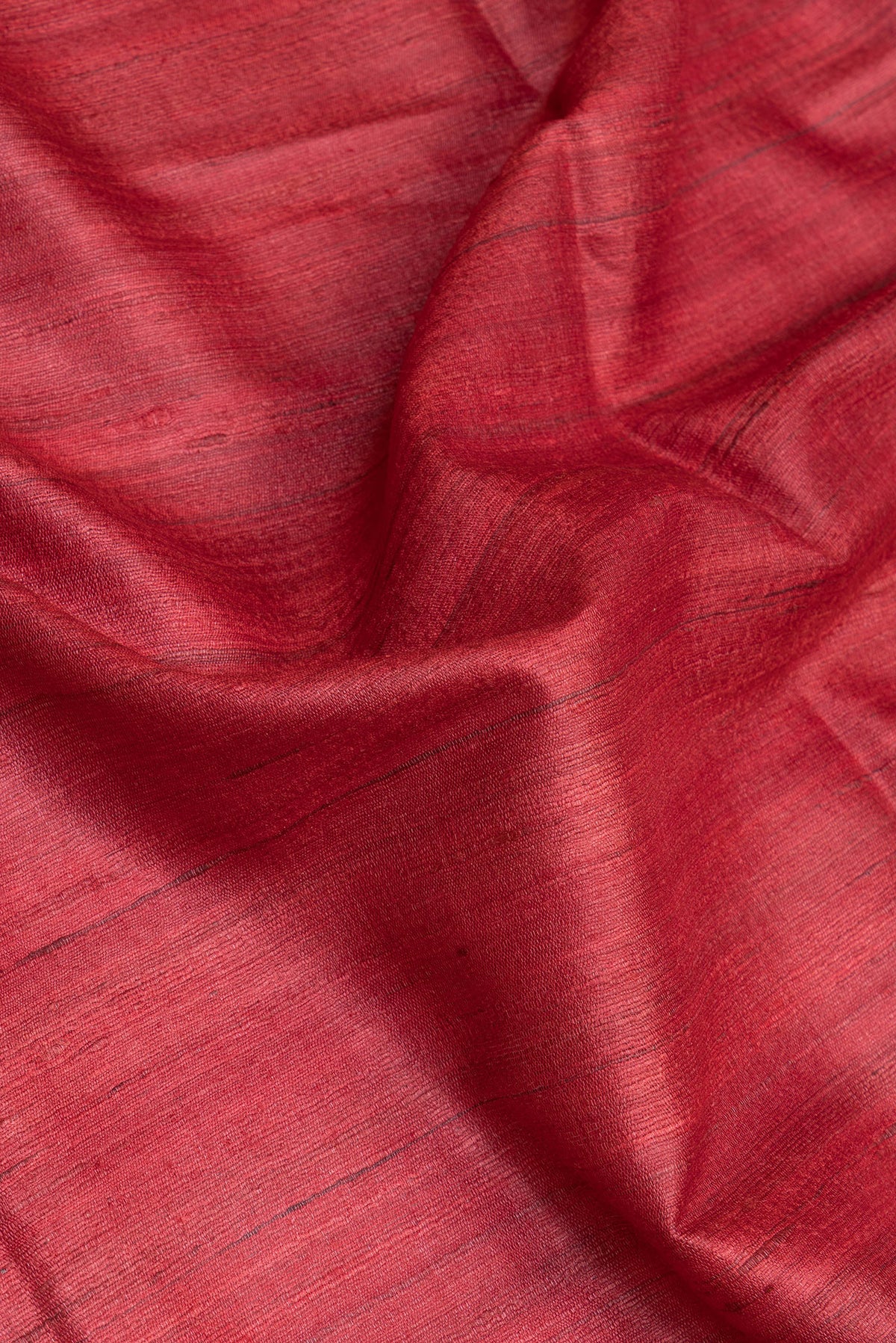 Close up of Red Tussar Silk Saree with Plain Body and Fancy Border.  displaying folds