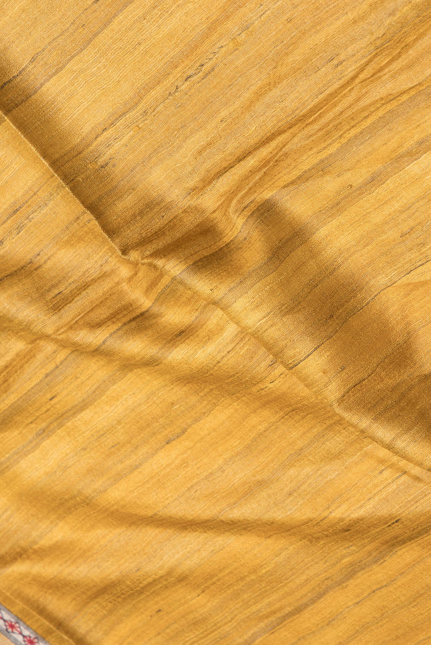 Close up of Mustard Tussar Silk Saree with Plain Body and Printed Border.  displaying folds
