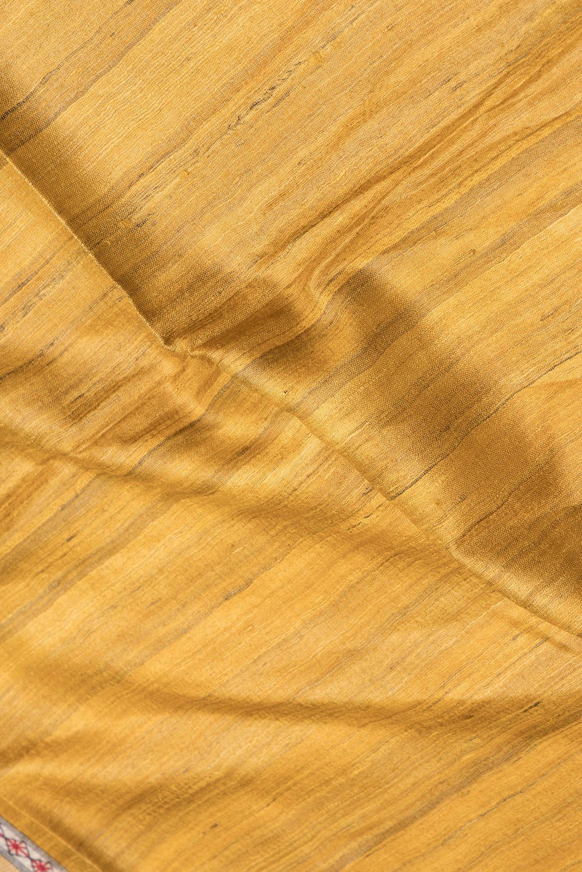 Close up of Mustard Tussar Silk Saree with Plain Body and Printed Border.  displaying folds
