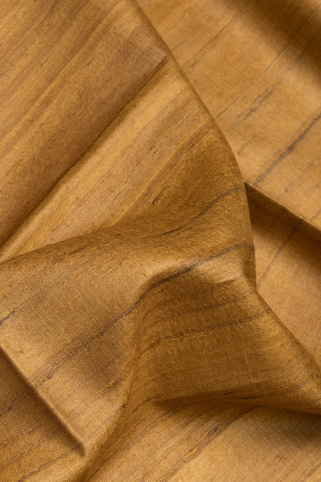 Close up of Mustard Tussar Silk Saree with Plain Body and Fancy Border.  displaying folds