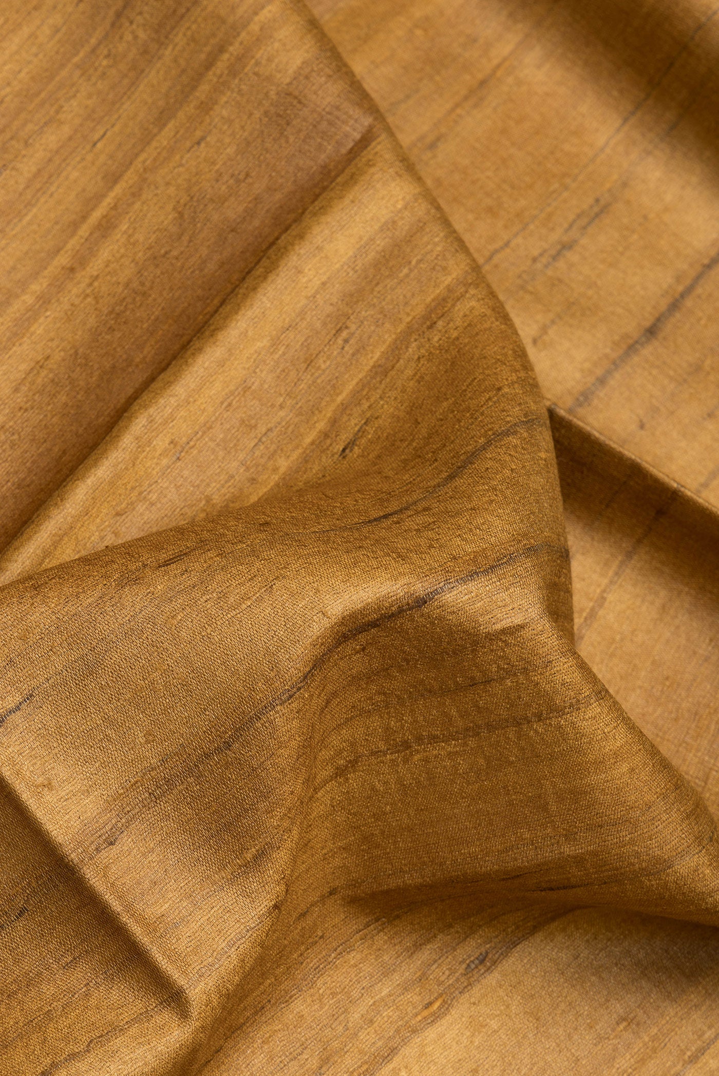 Close up of Mustard Tussar Silk Saree with Plain Body and Fancy Border.  displaying folds